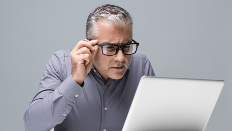 Man straining his eyes looking at a computer screen