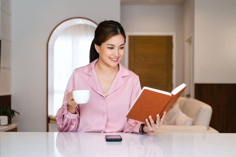 Woman drinking tea and reading a book at home
