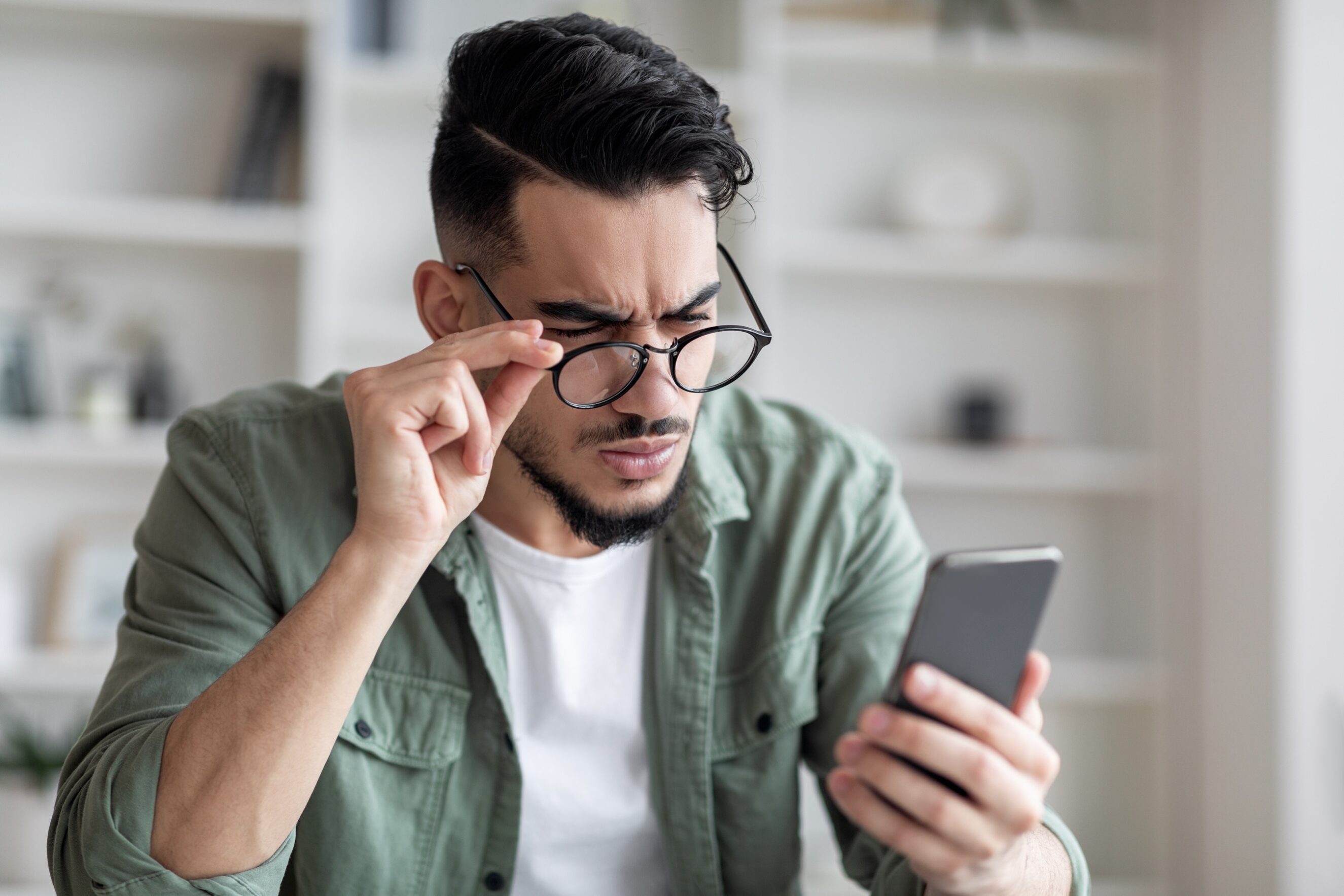 Man In Eyeglasses Looking At Smartphone Screen And Frownin